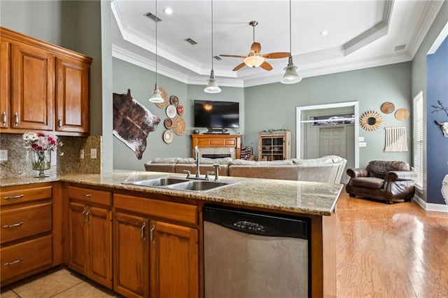 kitchen featuring dishwasher, a raised ceiling, open floor plan, and a sink