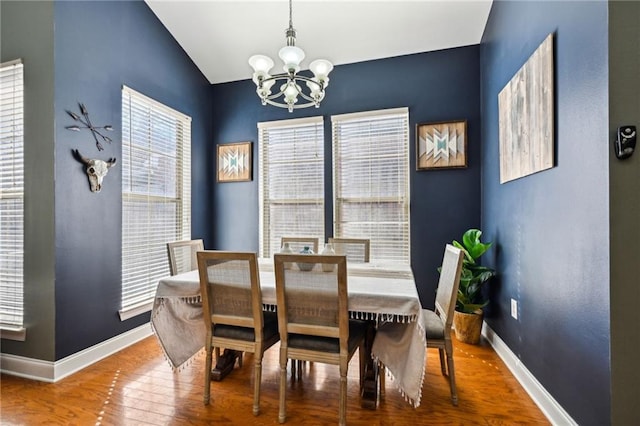 dining room with a notable chandelier, lofted ceiling, hardwood / wood-style flooring, and baseboards