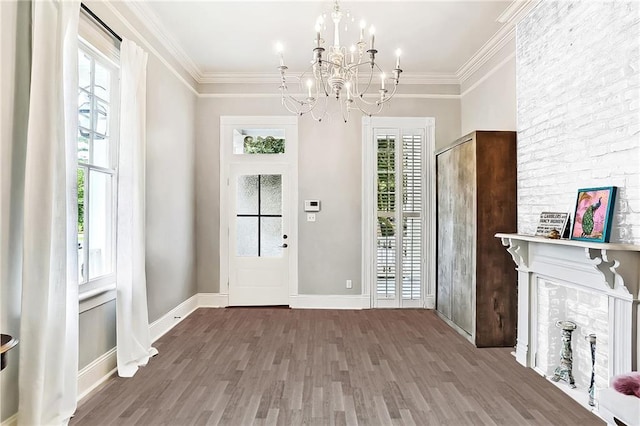 entryway featuring crown molding, wood finished floors, baseboards, and a chandelier