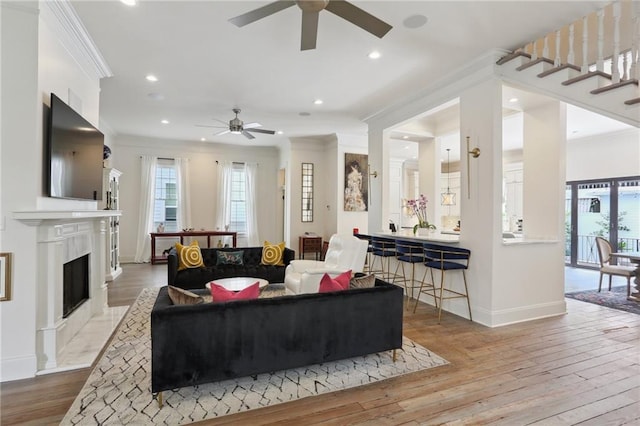 living area featuring a fireplace with flush hearth, crown molding, baseboards, and hardwood / wood-style floors