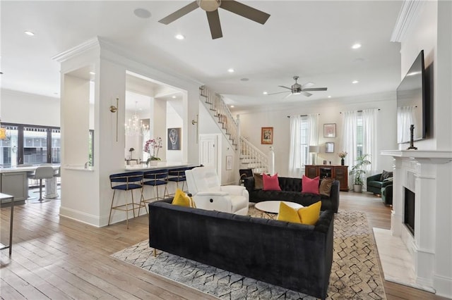 living area featuring hardwood / wood-style floors, stairway, a fireplace with flush hearth, crown molding, and a wealth of natural light