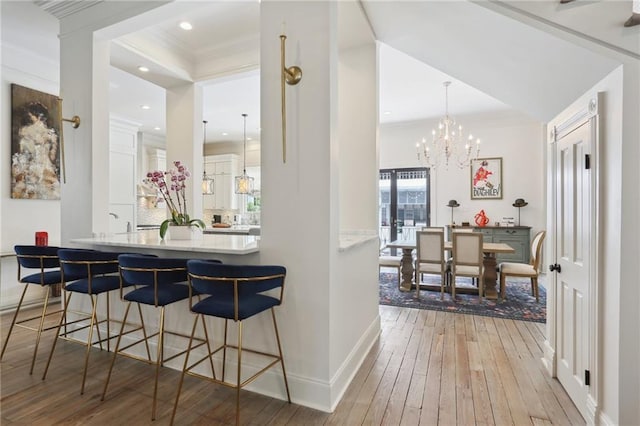 bar with hardwood / wood-style floors, an inviting chandelier, baseboards, and ornamental molding