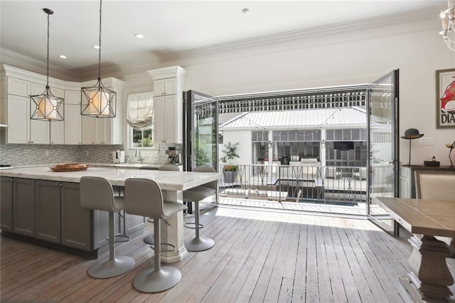 kitchen featuring pendant lighting, backsplash, a center island, crown molding, and dark wood-style flooring