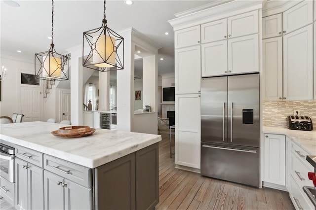 kitchen with light wood finished floors, decorative backsplash, stainless steel appliances, and ornamental molding