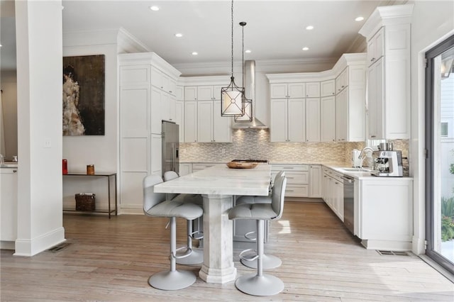 kitchen with stainless steel dishwasher, crown molding, wall chimney range hood, and a center island