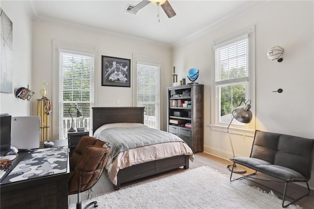 bedroom with visible vents, wood finished floors, baseboards, and ornamental molding