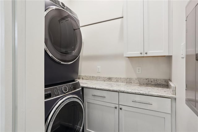 clothes washing area featuring cabinet space and stacked washer and clothes dryer