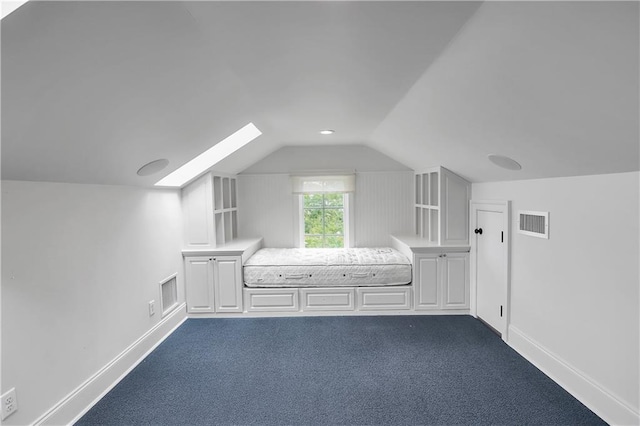 additional living space with visible vents, dark carpet, baseboards, and vaulted ceiling