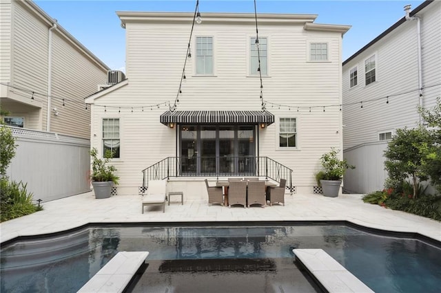 rear view of house with an outdoor pool, a patio, and fence