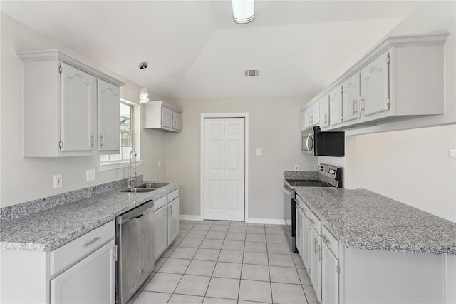 kitchen with stainless steel appliances, lofted ceiling, light tile patterned flooring, a sink, and baseboards