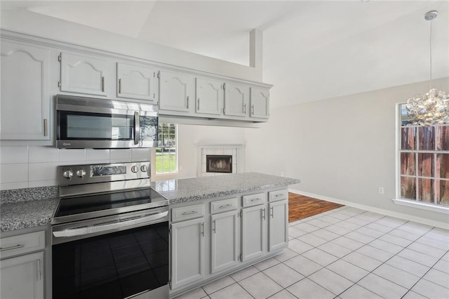 kitchen featuring baseboards, decorative backsplash, a peninsula, vaulted ceiling, and stainless steel appliances