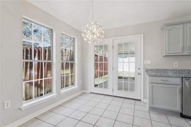 unfurnished dining area featuring light tile patterned floors, baseboards, and an inviting chandelier