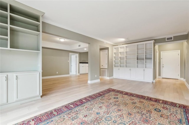 interior space with light wood finished floors, visible vents, baseboards, and crown molding