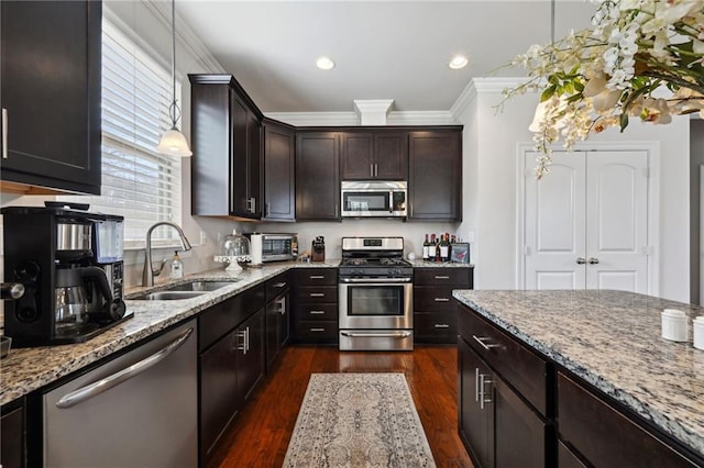 kitchen with crown molding, appliances with stainless steel finishes, dark wood-type flooring, a sink, and light stone countertops