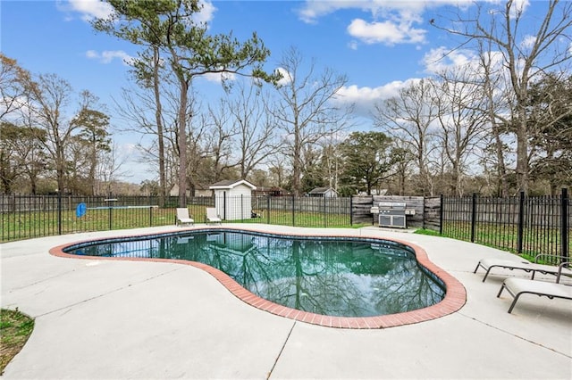 view of swimming pool featuring a patio area, a fenced backyard, a fenced in pool, and an outbuilding