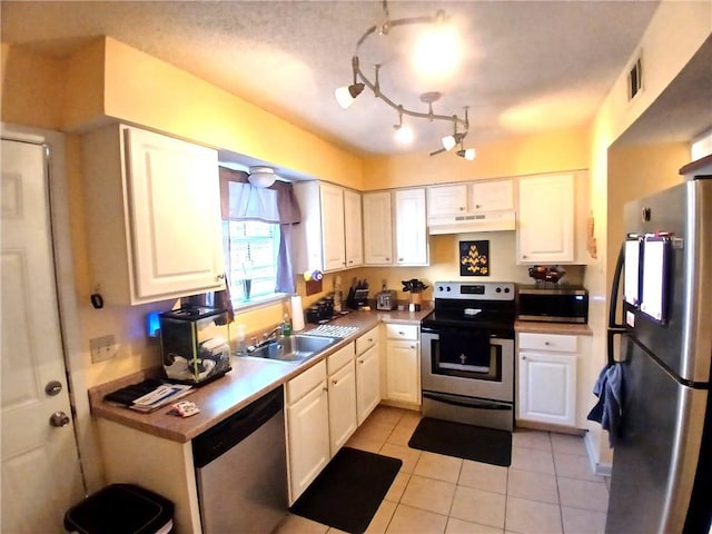 kitchen featuring light tile patterned floors, under cabinet range hood, a sink, white cabinets, and appliances with stainless steel finishes