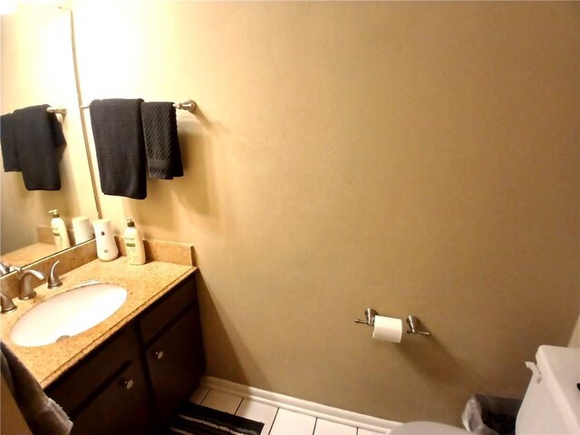 bathroom featuring toilet, tile patterned flooring, baseboards, and vanity