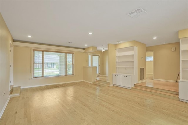 unfurnished living room with light wood-style floors, baseboards, and visible vents