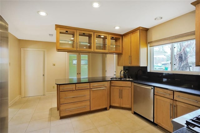 kitchen featuring a peninsula, a sink, dishwasher, brown cabinetry, and glass insert cabinets