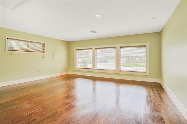 unfurnished room featuring baseboards, visible vents, and hardwood / wood-style floors