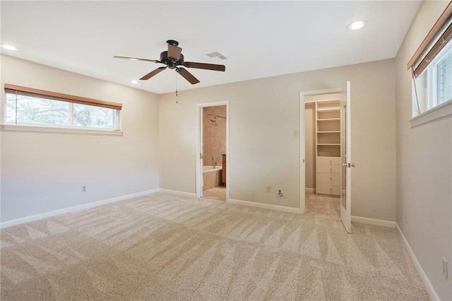 unfurnished bedroom with a spacious closet, recessed lighting, light colored carpet, and baseboards