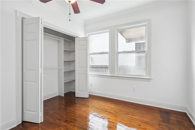 unfurnished bedroom featuring a closet, dark wood-style flooring, crown molding, and baseboards