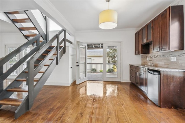 kitchen featuring light countertops, decorative backsplash, ornamental molding, a sink, and dishwasher