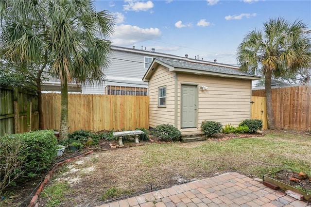 back of property with a fenced backyard, a lawn, and an outbuilding