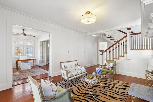 living room featuring stairway, baseboards, ornamental molding, and wood finished floors