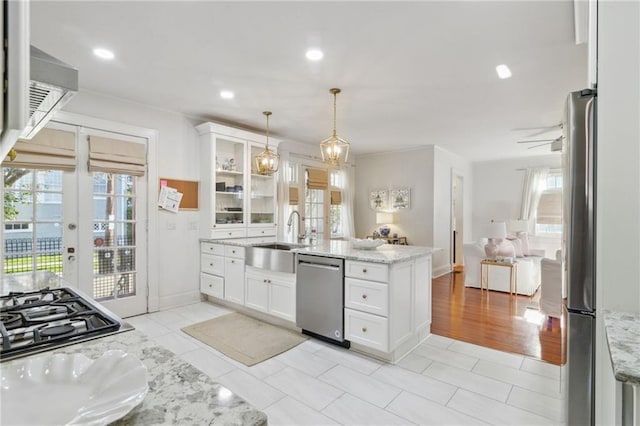 kitchen featuring glass insert cabinets, stainless steel appliances, french doors, white cabinetry, and a sink