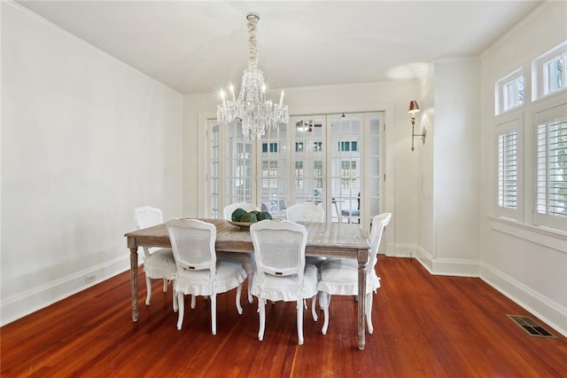 dining area featuring a notable chandelier, wood finished floors, visible vents, and baseboards