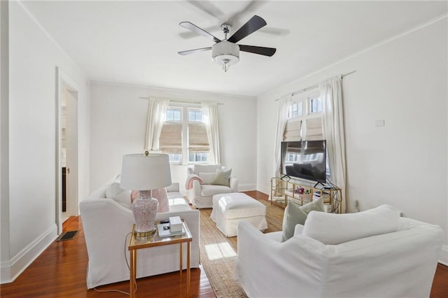 living room featuring ceiling fan, ornamental molding, wood finished floors, and baseboards