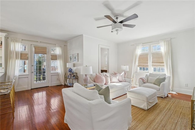 living area featuring wood-type flooring, baseboards, a ceiling fan, and ornamental molding