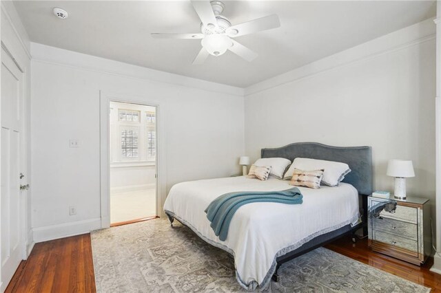 bedroom featuring wood finished floors, a ceiling fan, and baseboards