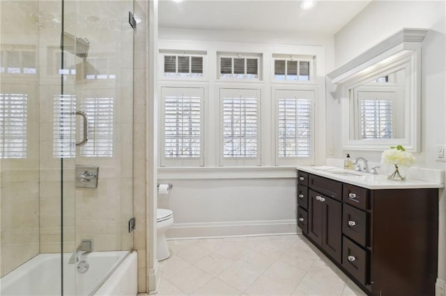 bathroom featuring shower / bath combination with glass door, toilet, vanity, tile patterned flooring, and baseboards