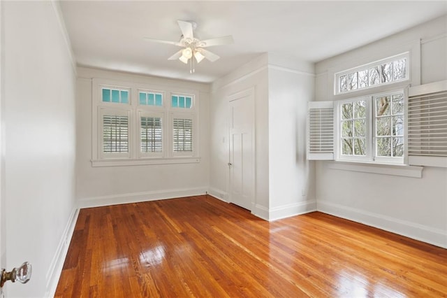 empty room featuring wood-type flooring, baseboards, and ceiling fan