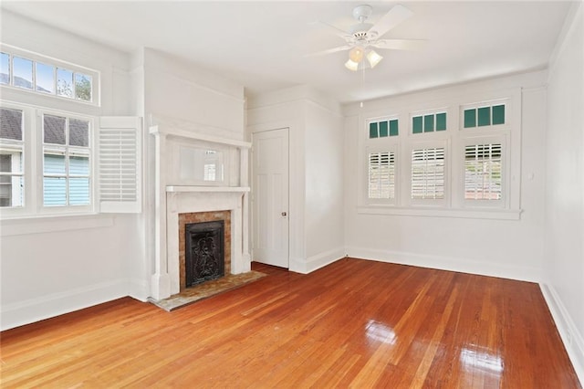 unfurnished living room featuring light wood finished floors, a fireplace, a ceiling fan, and baseboards