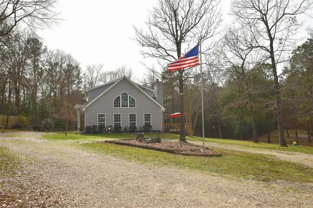 view of side of home with driveway, a chimney, and a lawn