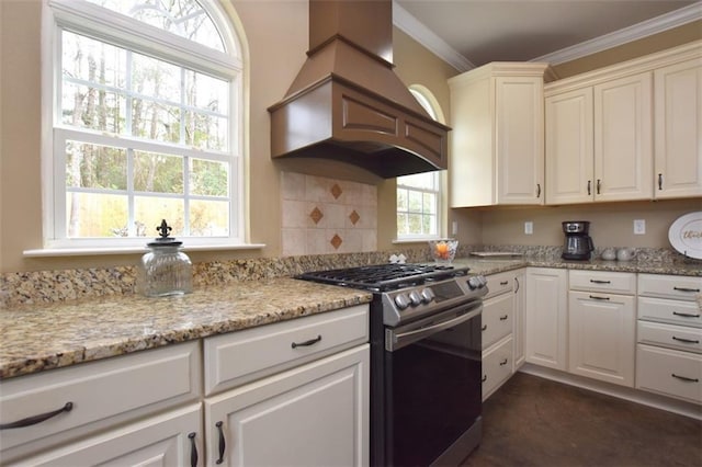 kitchen featuring light stone counters, stainless steel gas range oven, white cabinetry, ornamental molding, and custom range hood