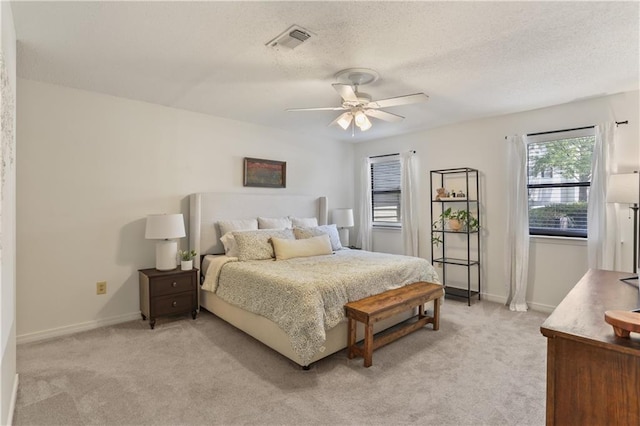 bedroom featuring light carpet, baseboards, visible vents, and a textured ceiling