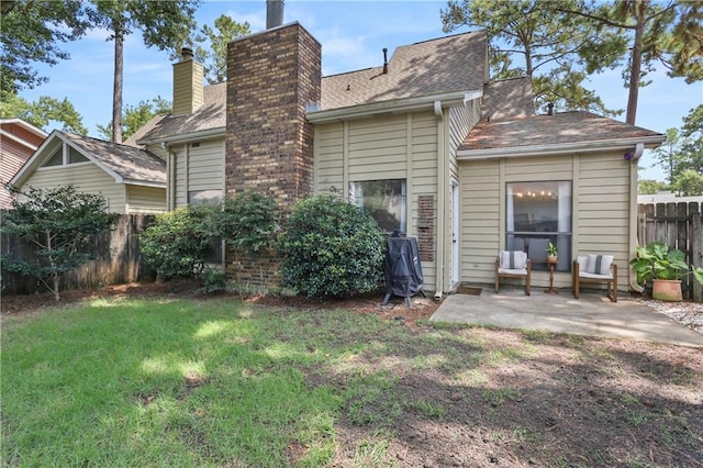 back of property with fence, roof with shingles, a lawn, a chimney, and a patio area