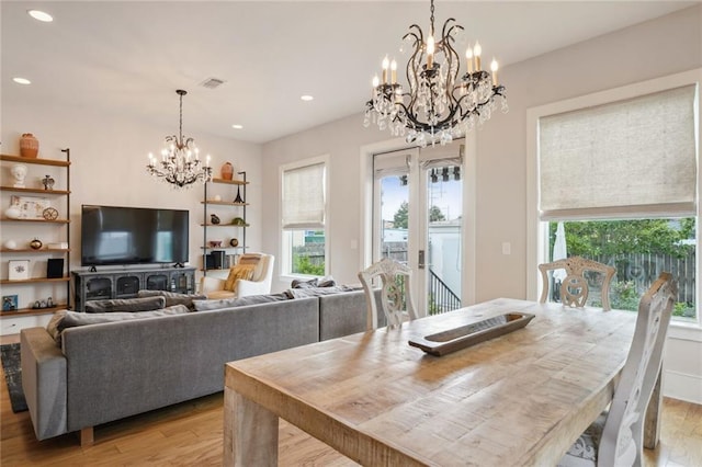 dining space with french doors, light wood finished floors, recessed lighting, and a notable chandelier