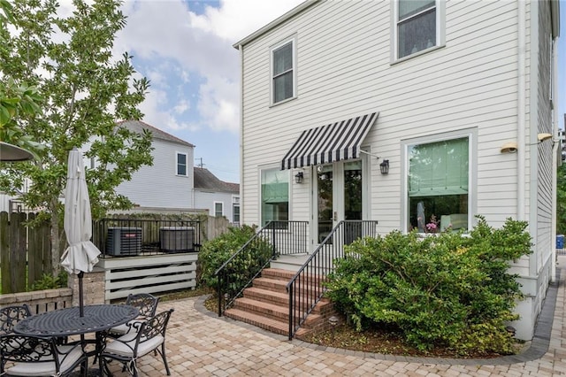 rear view of house with outdoor dining space, a patio, and fence