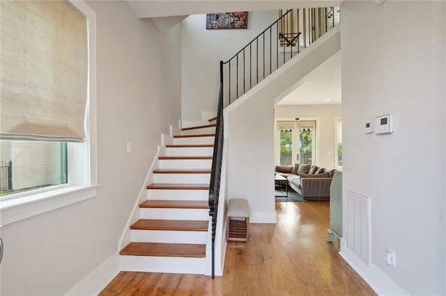 stairway with baseboards, visible vents, a towering ceiling, wood finished floors, and french doors