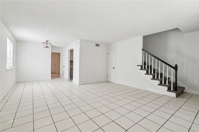 unfurnished living room featuring stairs, light tile patterned floors, visible vents, and baseboards