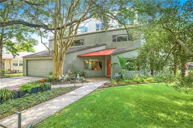 view of front of house with driveway, a front yard, and stucco siding