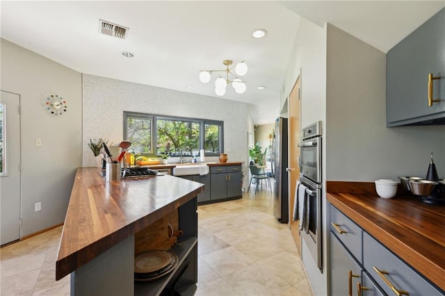 kitchen with a peninsula, butcher block countertops, visible vents, and appliances with stainless steel finishes