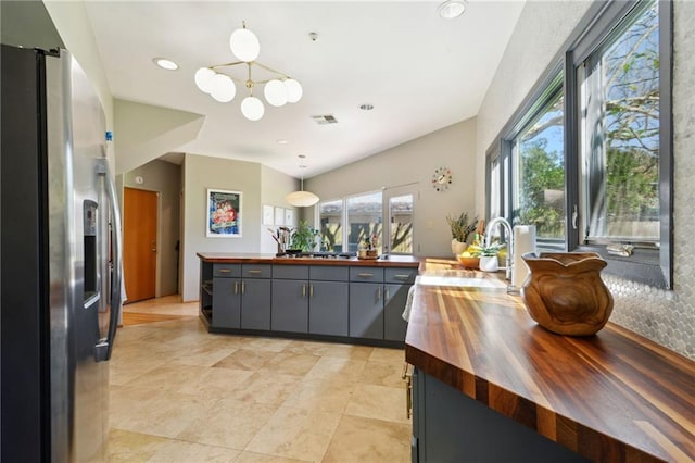 kitchen featuring stainless steel refrigerator with ice dispenser, butcher block counters, visible vents, gray cabinetry, and a sink