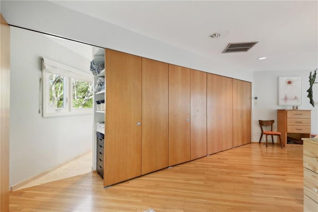 corridor featuring baseboards, visible vents, and light wood-style floors