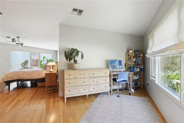 bedroom featuring lofted ceiling, multiple windows, visible vents, and wood finished floors